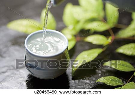Stock Image - Sake being poured into a cup. Fotosearch