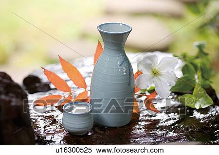 Saki bottle and cup on a rock next to a white flower View Large Photo Image Stock Photography - Saki bottle and cup on a rock next to a white flower. Fotosearch
