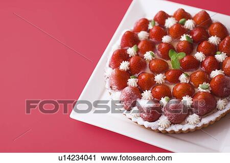 Stock Image - Strawberry tart on plate, red background. Fotosearch