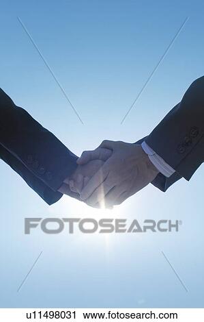 Two businessmen shaking hands under the sun View Large Photo Image Stock Image - Two businessmen shaking hands under the sun. Fotosearch