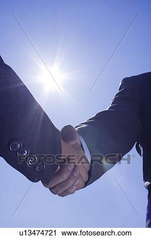 Two businessmen shaking hands under the sun View Large Photo Image Stock Image - Two businessmen shaking hands under the sun. Fotosearch