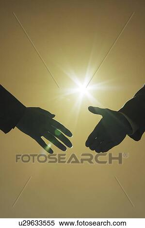 Stock Photography - Two businessmen shaking hands under the sun. Fotosearch