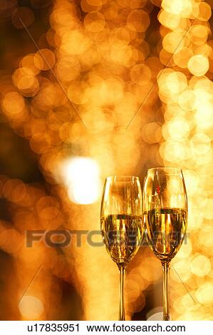 Two champagne glasses toasting with defocused fairy lights in the background View Large Photo Image Stock Image - Two champagne glasses toasting with defocused fairy lights in the background. Fotosearch