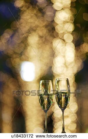 Two champagne glasses toasting with defocused fairy lights in the background View Large Photo Image Stock Image - Two champagne glasses toasting with defocused fairy lights in the background. Fotosearch