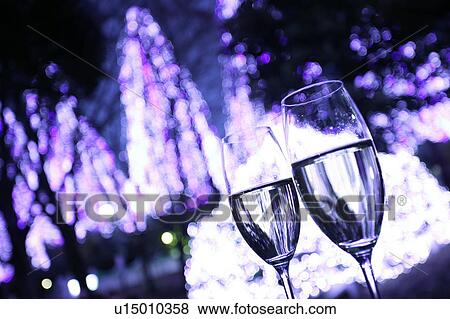 Two champagne glasses toasting with illuminated purple Christmas trees in the background View Large Photo Image Stock Photo - Two champagne glasses toasting with illuminated purple Christmas trees in the background. Fotosearch