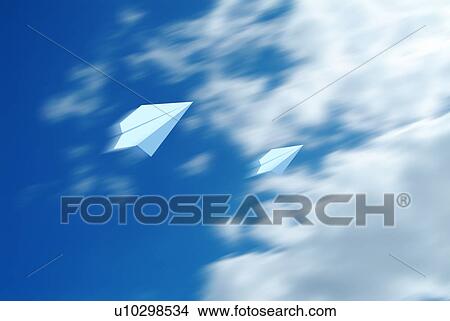 Picture - Two paper airplanes flying against a blue cloudy sky. Fotosearch