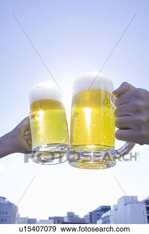 Two people toasting glass of beer under the sky View Large Photo Image Stock Photo - Two people toasting glass of beer under the sky. Fotosearch