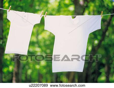 Two T-shirts hanging side by side on a washing line View Large Photo Image Stock Photo - Two T-shirts hanging side by side on a washing line. Fotosearch