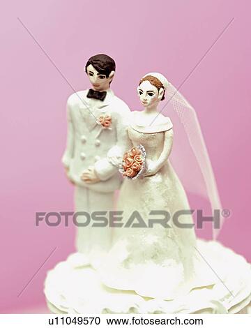 Wedding cake topped with bride and groom figurines View Large Photo Image Stock Image - Wedding cake topped with bride and groom figurines. Fotosearch