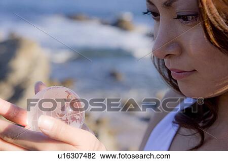 Stock Image - Young woman holding globe in hands, close up. Fotosearch