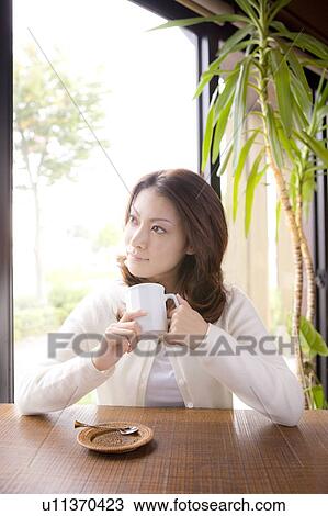 Young woman holding mug in cafe, looking away View Large Photo Image Stock Image - Young woman holding mug in cafe, looking away. Fotosearch