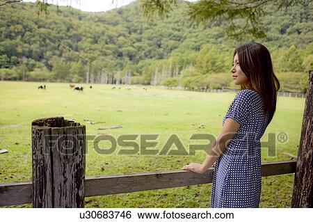 Stock Photograph - Young woman looking at pasture, Tochigi prefecture, Japan. Fotosearch