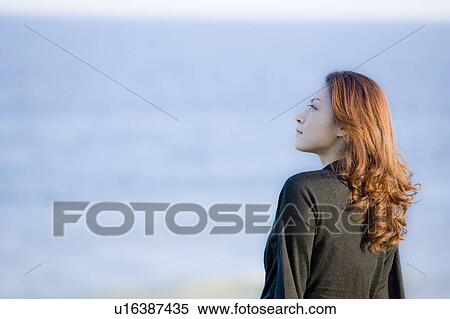 Young woman sitting on beach, looking away, copy space View Large Photo Image Stock Photography - Young woman sitting on beach, looking away, copy space. Fotosearch