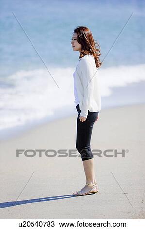 Stock Image - Young woman standing on beach. Fotosearch