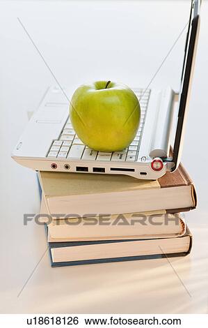 Stock Photograph - Apple on laptop and books. Fotosearch