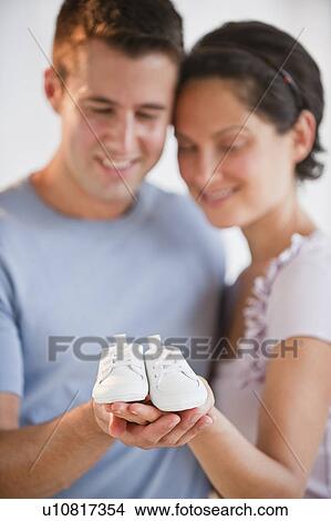 Picture - Couple holding baby shoes. Fotosearch