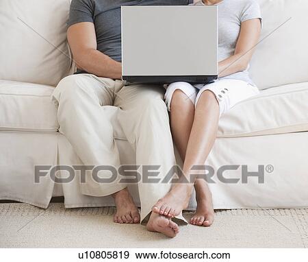 Stock Photo - Couple on sofa with laptop. Fotosearch