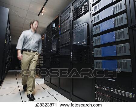 Stock Image - Man walking through data center. Fotosearch