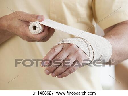 Stock Photo - Man wrapping hand in tensor bandage. Fotosearch