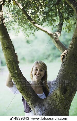 Smiling woman behind tree View Large Photo Image Stock Image - Smiling woman behind tree. Fotosearch