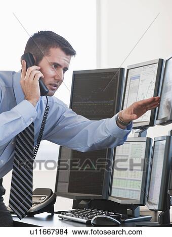 Picture - Trader studying computer screens. Fotosearch