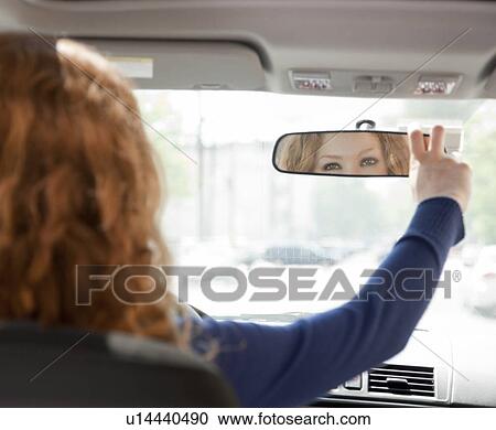 Stock Image - Woman adjusting driving mirror. Fotosearch