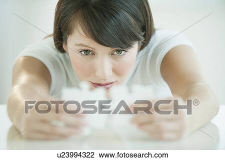 Stock Image - Woman holding puzzle pieces. Fotosearch