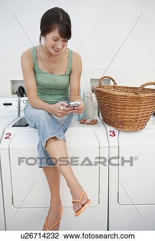 Stock Image - Woman in laundromat. Fotosearch