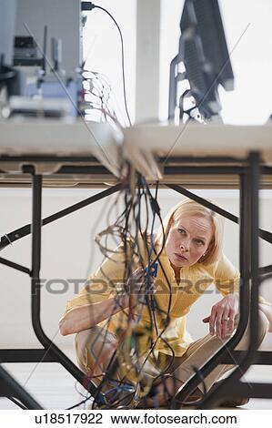 Stock Image - Woman under table working on networked computers. Fotosearch