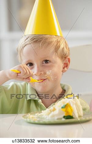Stock Image - Young child eating birthday cake. Fotosearch