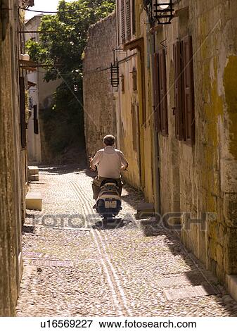 Back view of man riding a scooter in Rhodes Greece View Large Photo Image Stock Photo - Back view of man riding a scooter in Rhodes Greece. Fotosearch