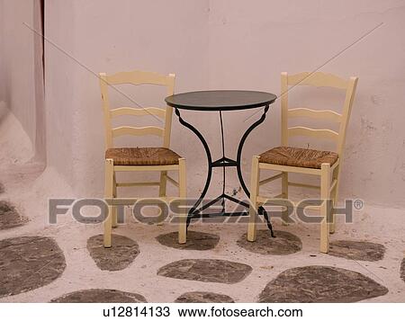 Stock Image - Empty table and chairs in Mykonos Greece. Fotosearch