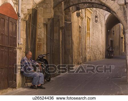Stock Photograph - Man sitting on passageway in Rhodes Greece. Fotosearch