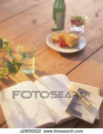 Stock Image - A book and a glass of water on a wooden table. Fotosearch