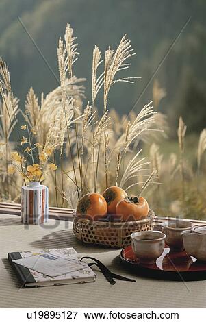 Stock Photo - A bowl of persimmons with Japanese pampas grass in the background. Fotosearch