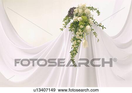 Stock Photo - A formal arrangement of flowers on an elegantly-draped white cloth background. Fotosearch
