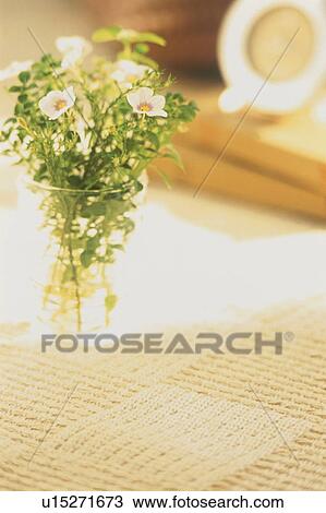 Stock Image - A vase of flowers on a textured tablecloth. Fotosearch