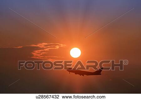 Stock Image - An Airplane Silhouetted in Front of the Morning Sun. Fotosearch