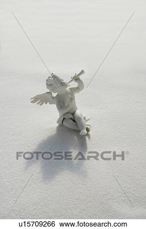 Stock Photograph - Angel figurine with musical instruments on white sand. Fotosearch