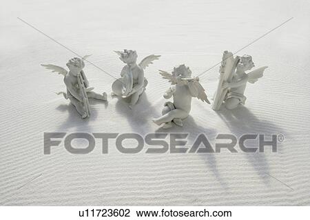 Angel figurines with musical instruments on white sand View Large Photo Image Stock Image - Angel figurines with musical instruments on white sand. Fotosearch