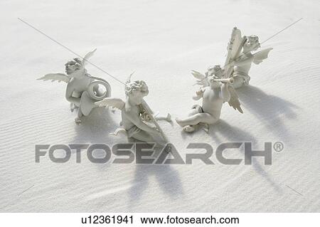Angel figurines with musical instruments on white sand View Large Photo Image Stock Image - Angel figurines with musical instruments on white sand. Fotosearch