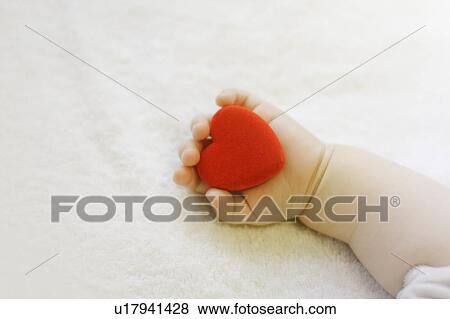Stock Photo - Baby holding red heart. Fotosearch