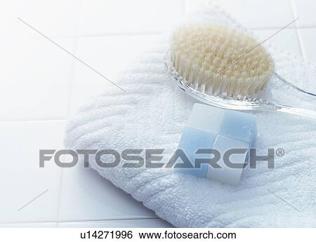 Stock Photograph - Bar of soap, back brush and towel in the bathroom. Fotosearch