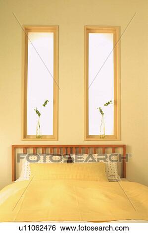 Stock Photograph - Bed in bedroom beneath windows. Fotosearch