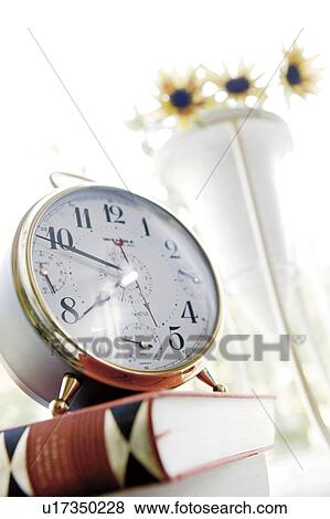 Stock Photo - Bedside table with flowers, book and alarm clock. Fotosearch