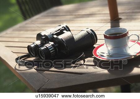 Binoculars and a cup of coffee on table View Large Photo Image Stock Photo - Binoculars and a cup of coffee on table. Fotosearch