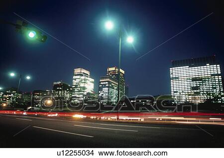 Picture - Blurred cars on road in front of city. Chiyoda-ku, Tokyo, Japan. Fotosearch