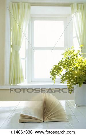 Stock Photo - Book on a table with pages fluttering in wind from window. Fotosearch