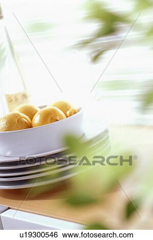 Stock Photograph - Bowl of lemons on stacked plates. Fotosearch