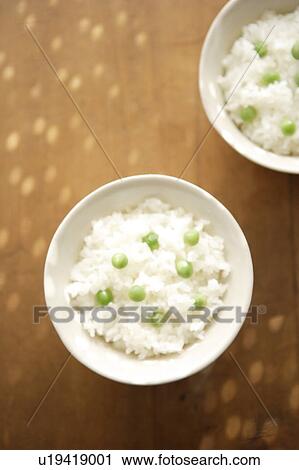 Stock Image - Bowls of rice with green peas. Fotosearch